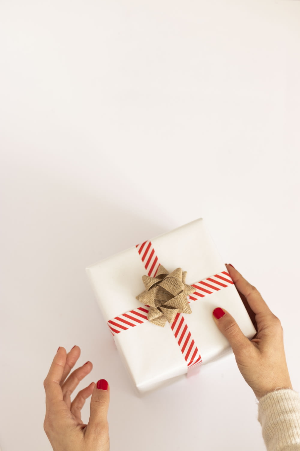 Persona sosteniendo una caja de regalo blanca y roja