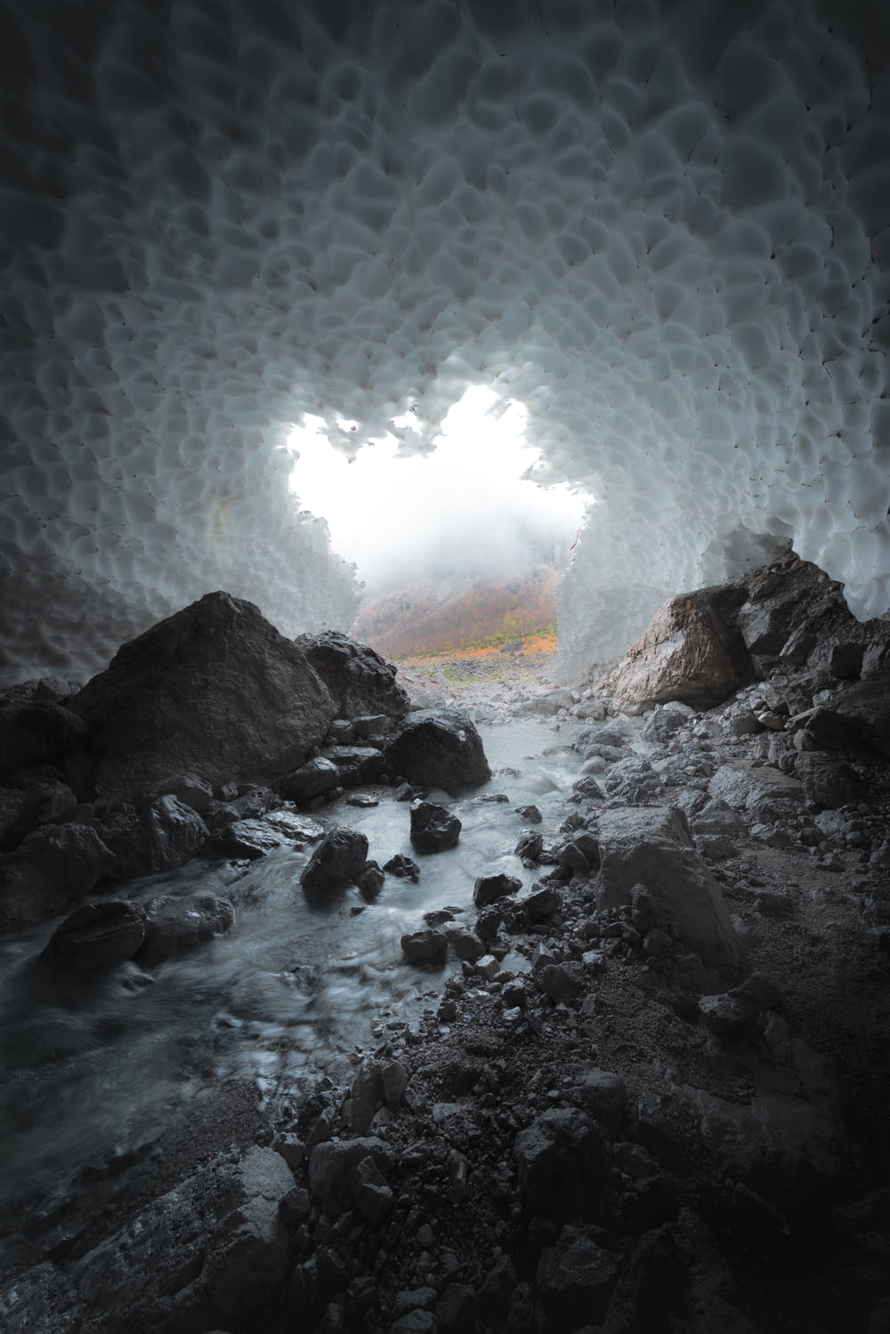 a cave filled with rocks and water under a cloudy sky