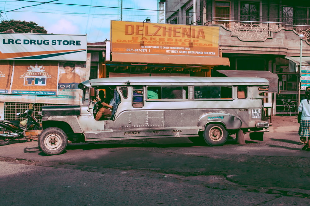 gray jeepney parked in front of house