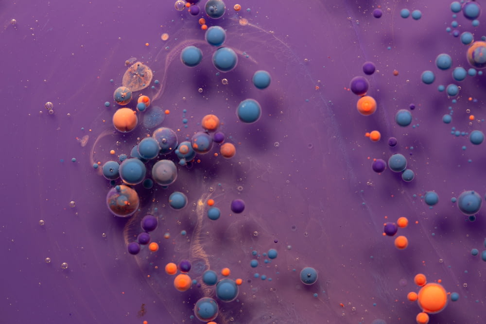 a close up of a purple surface with orange and blue balls
