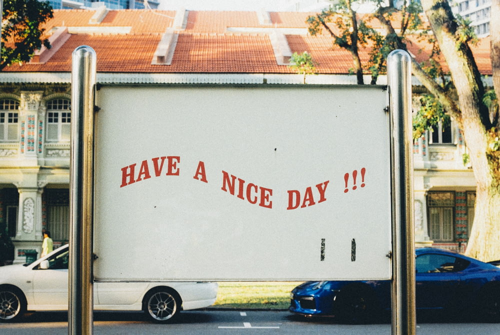 white and blue vehicles on road and have a nice day text on post