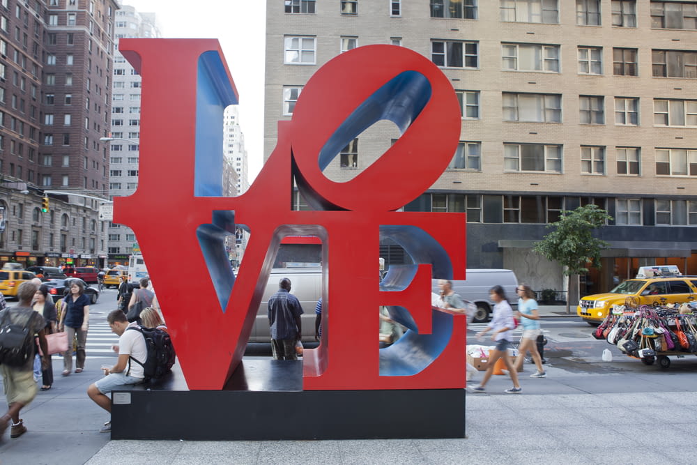people surrounding LOVE text statue