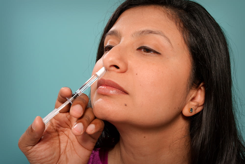 Una mujer se está poniendo una sy en la nariz