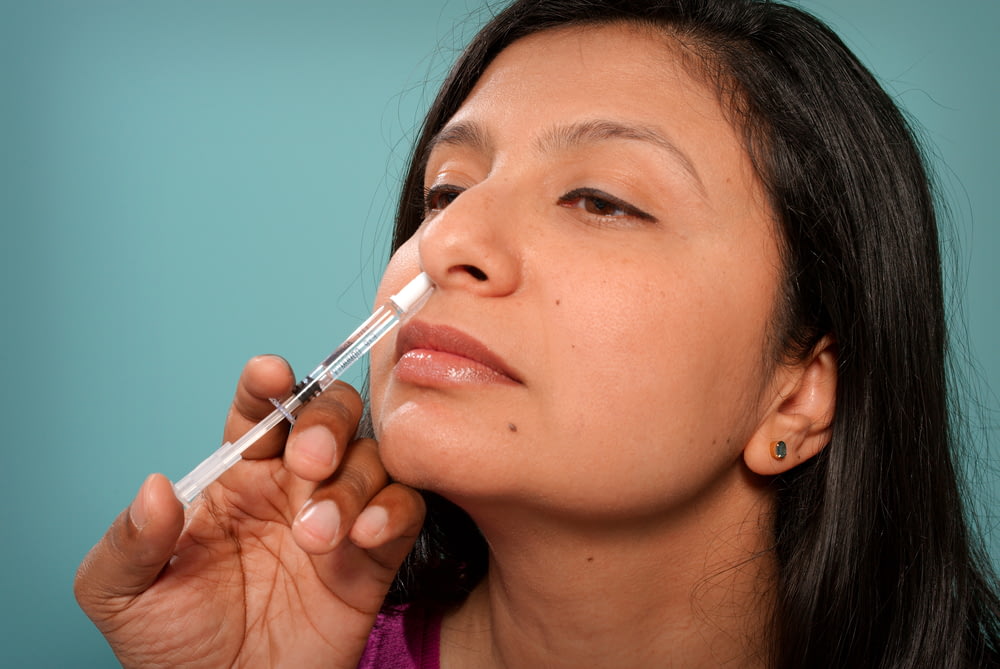 uma mulher está colocando um sy em seu nariz