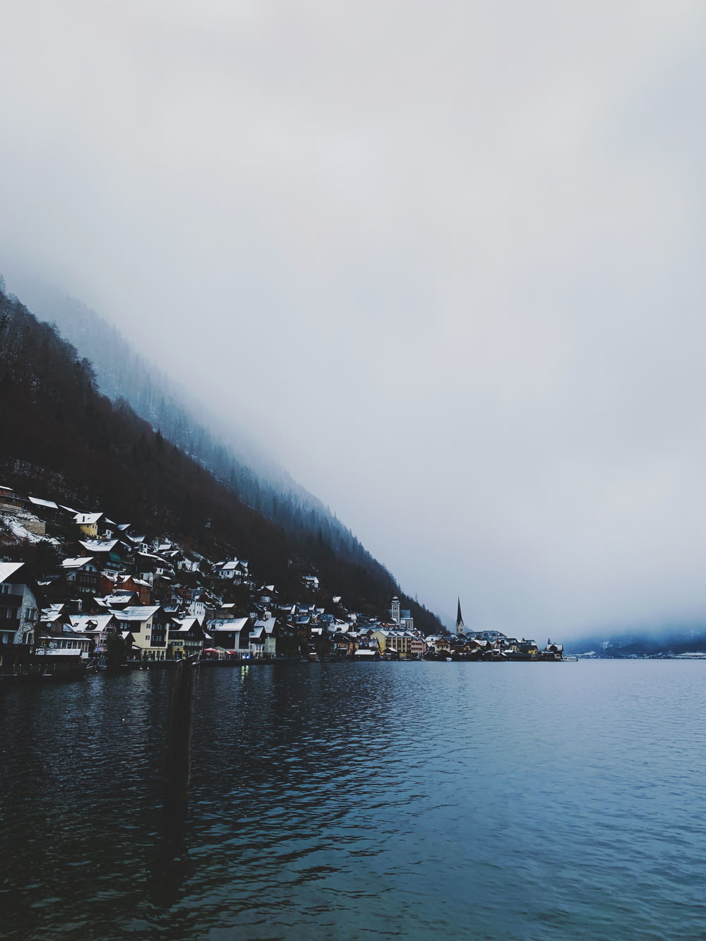 houses near body of water viewing mountain in foggy day