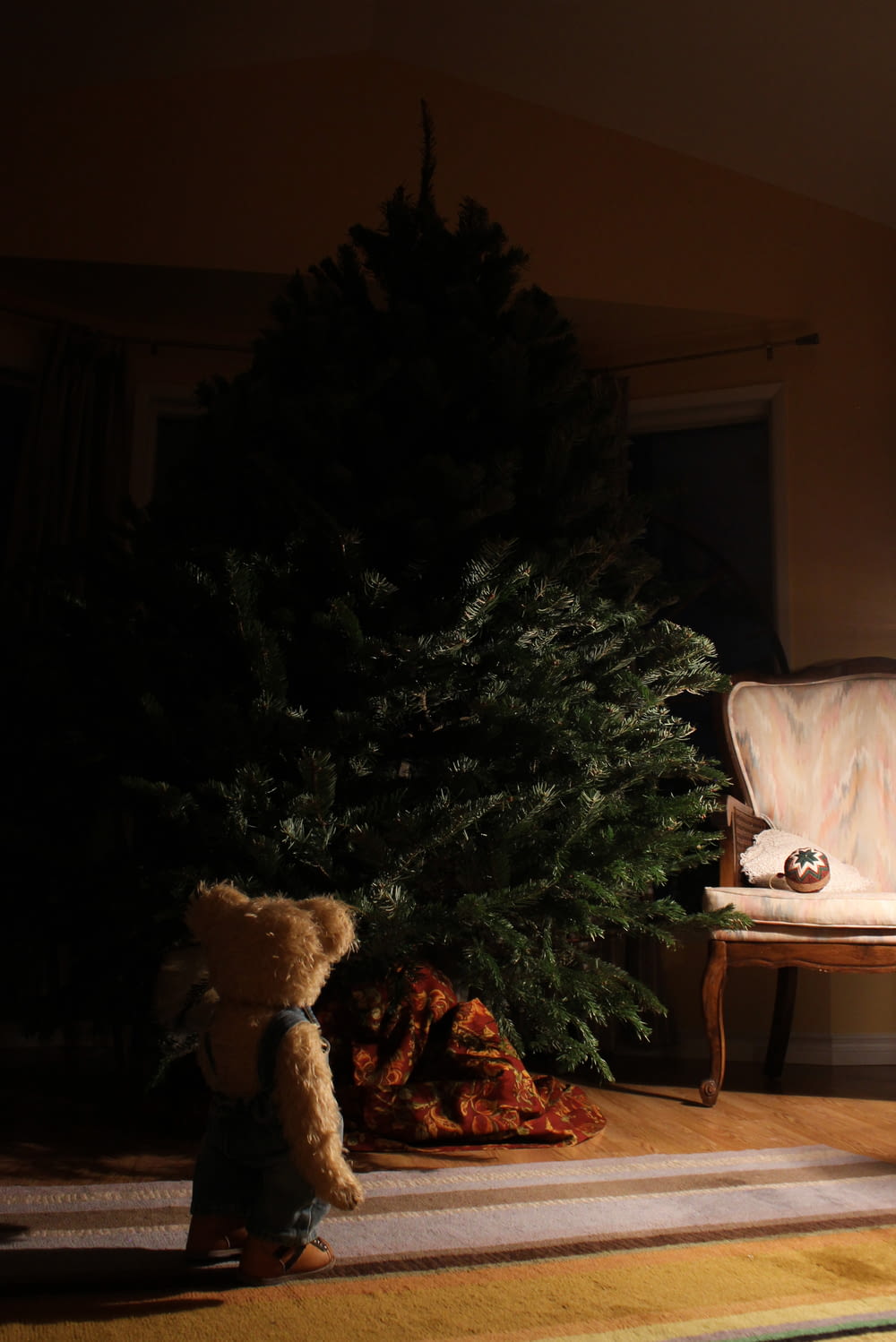 brown bear plush toy in front of green holiday tree