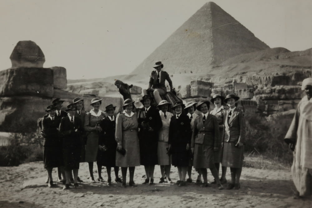 grayscale photo of group of women standing in front of pyramid
