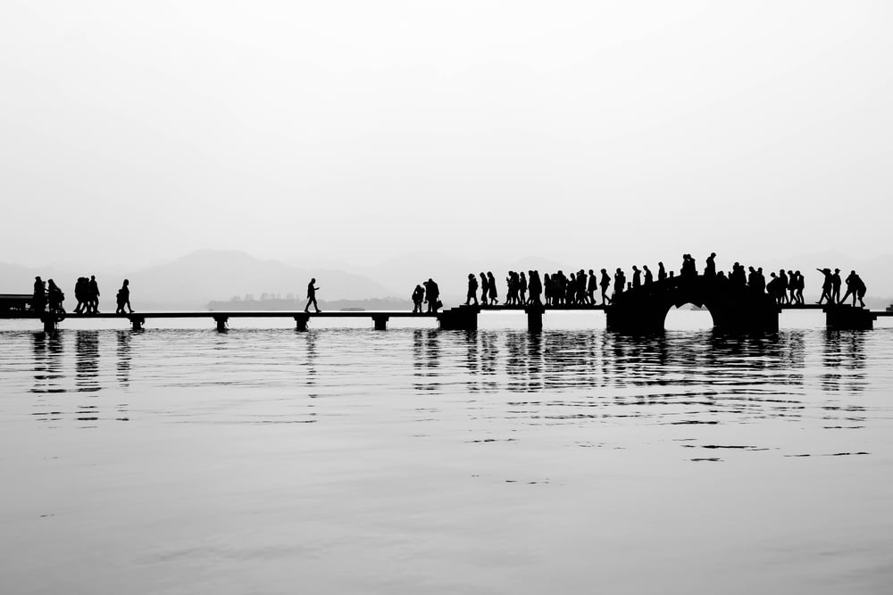 a group of people standing on a bridge over water