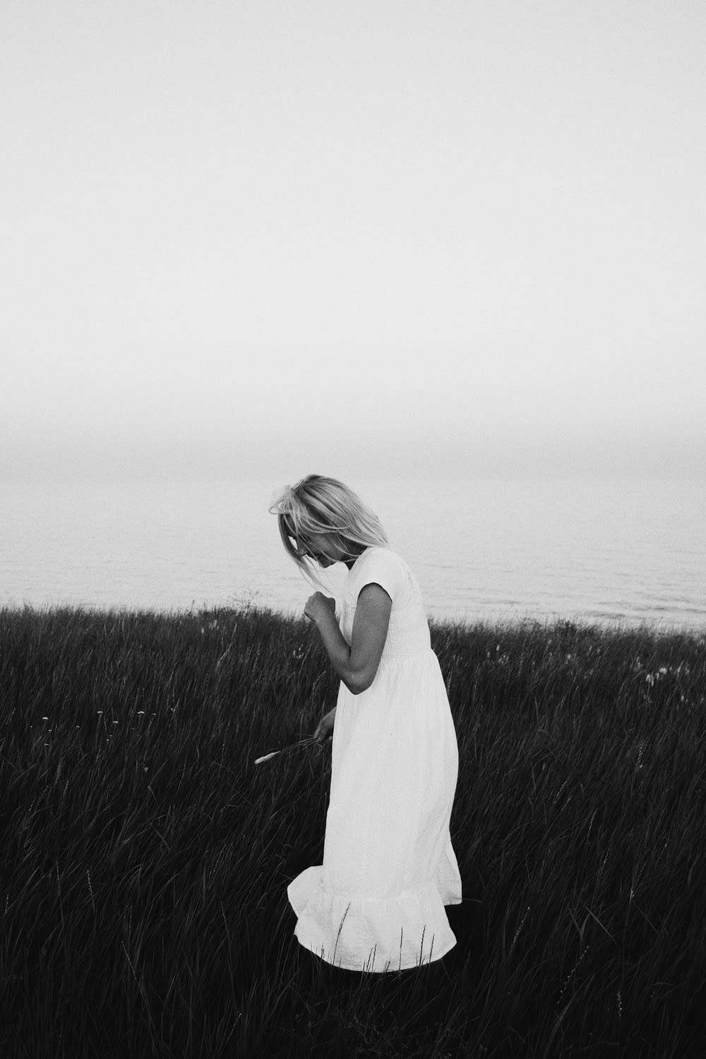 grayscale photography of woman wearing dress standing while looking down