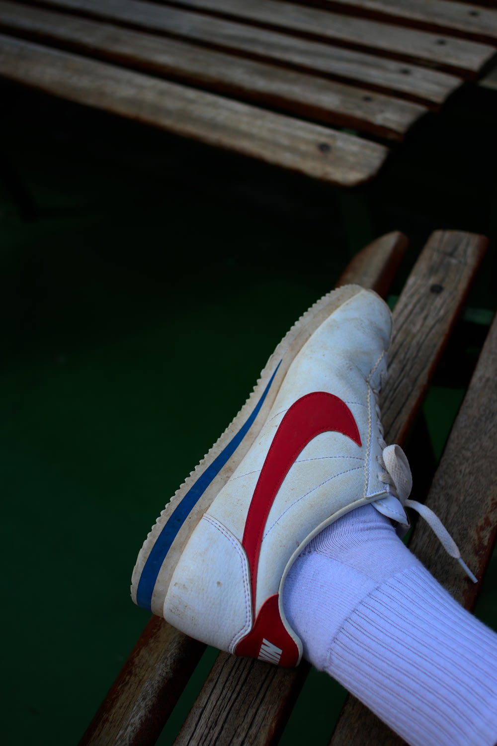 person wearing white and red with blue Nike sneaker