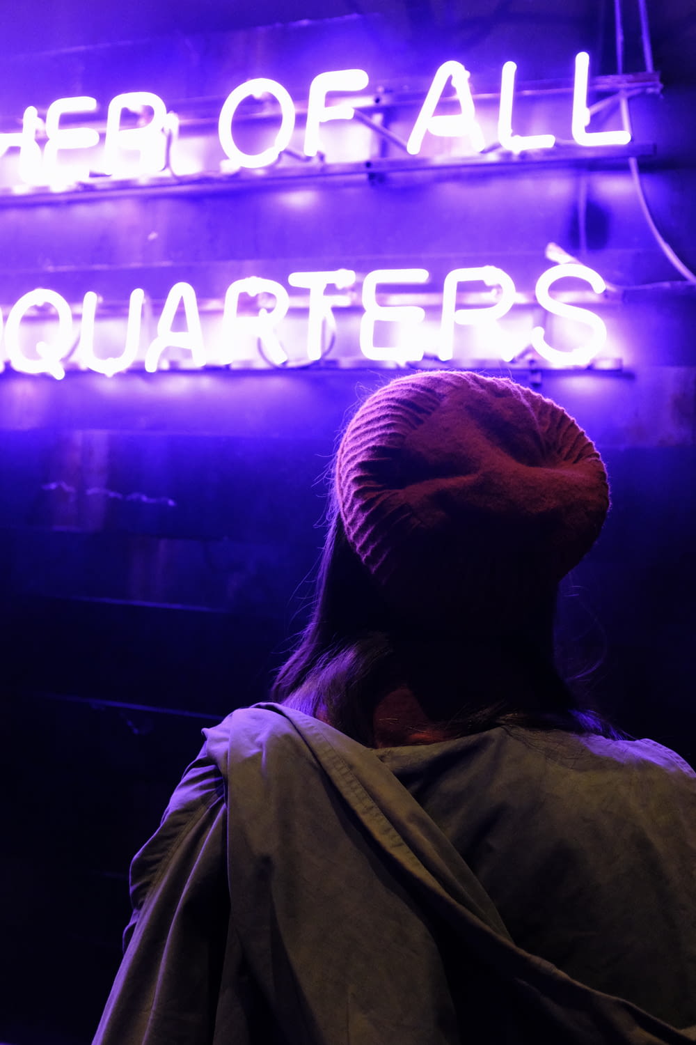 person wearing maroon knit cap in front of neon light signage
