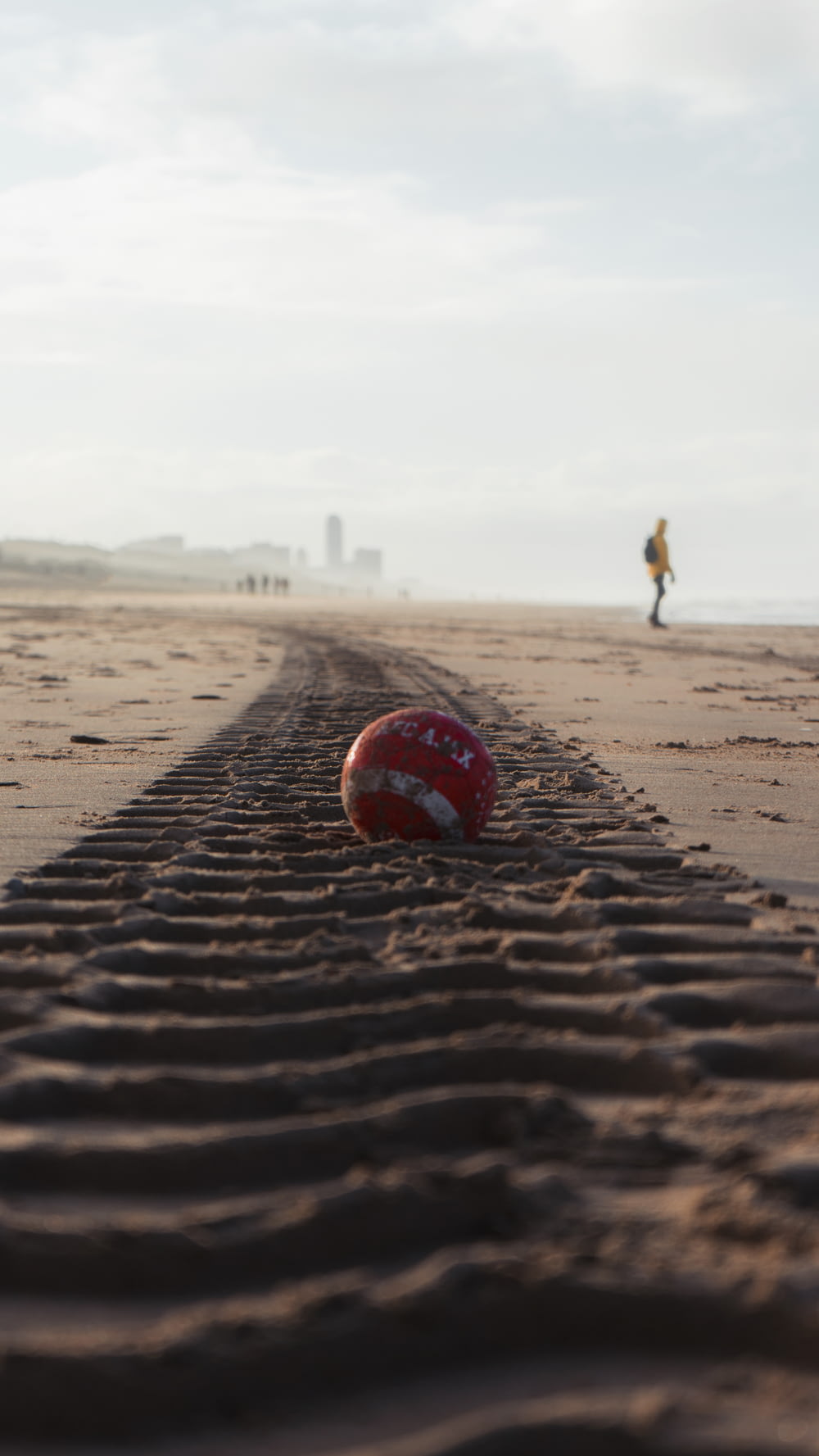 pallone da calcio rosso e bianco su sabbia marrone durante il giorno