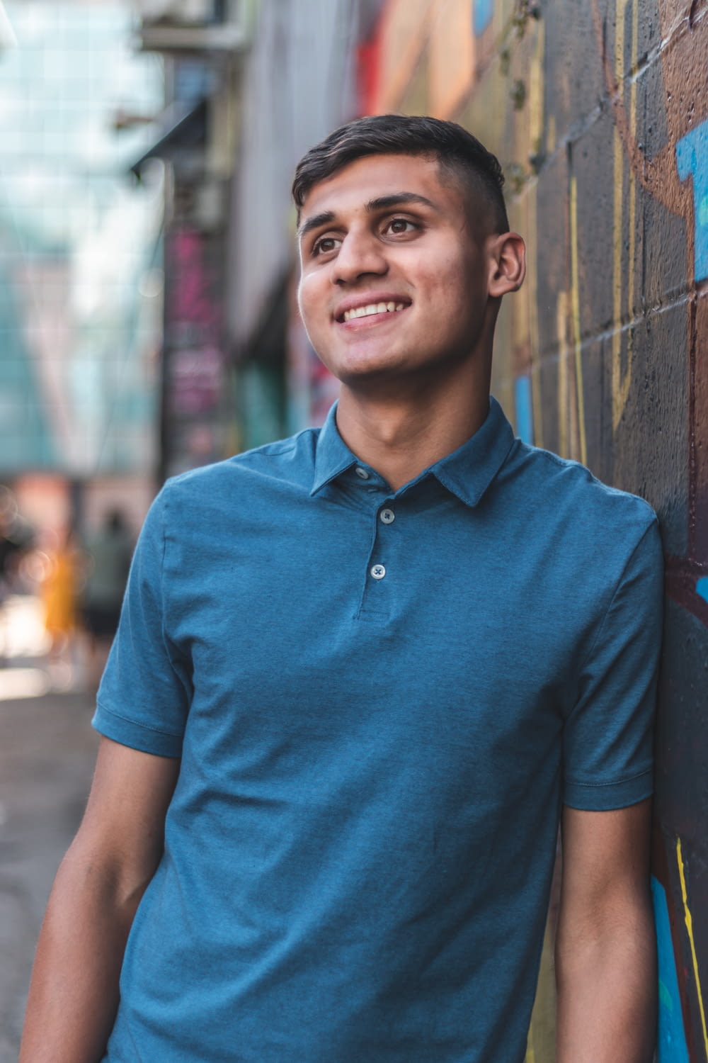 a man in a blue shirt leaning against a wall