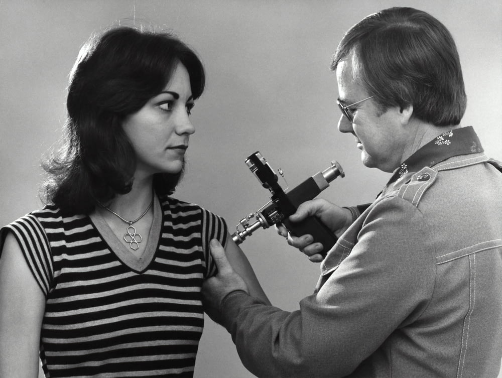 uma mulher está segurando um microscópio e um homem está olhando para ele