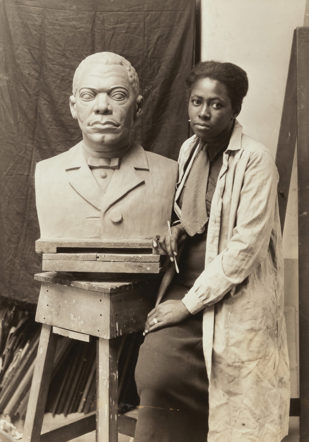 grayscale photography of woman standing beside man bust statue