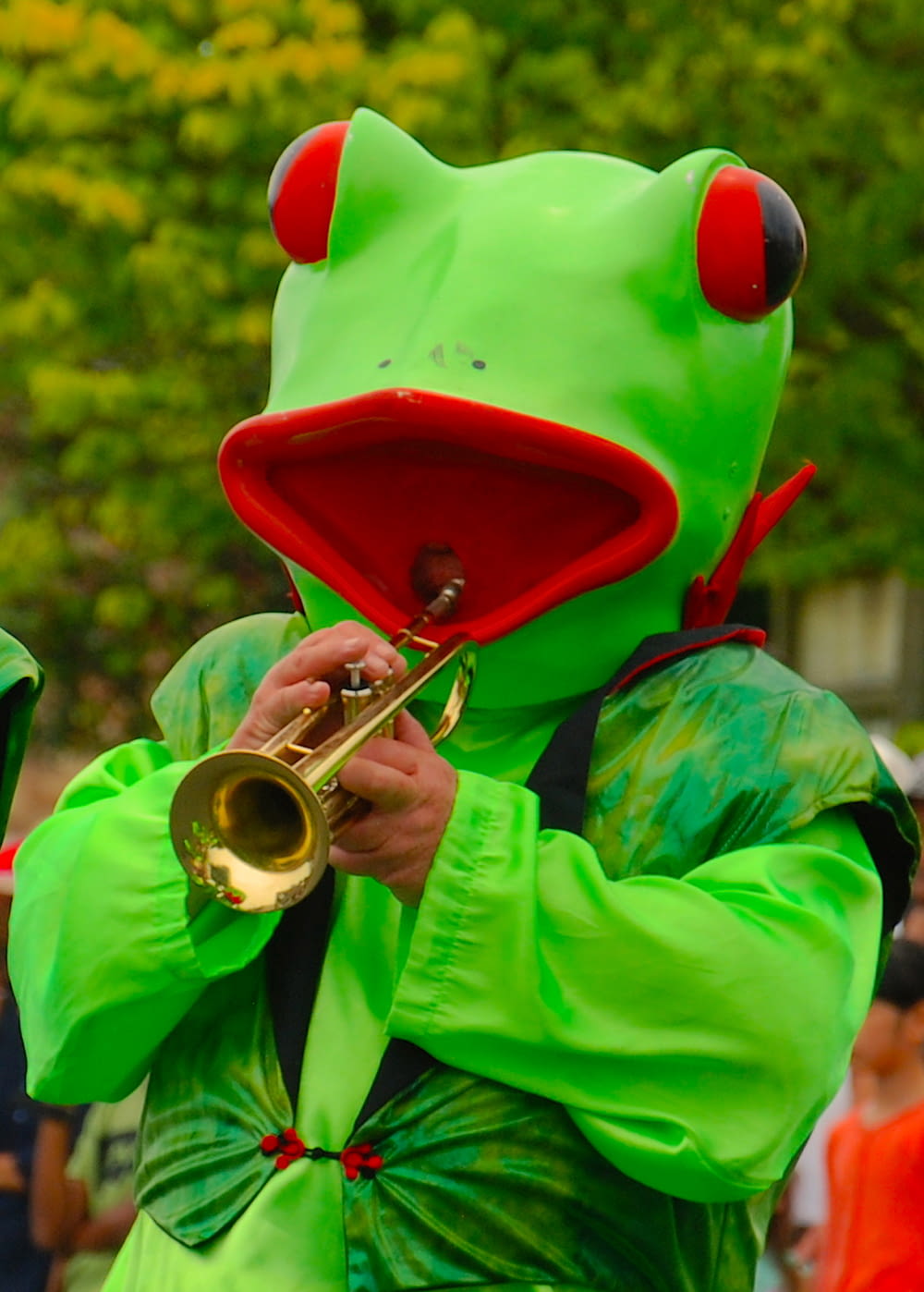 person in frog costume while playing trumpet