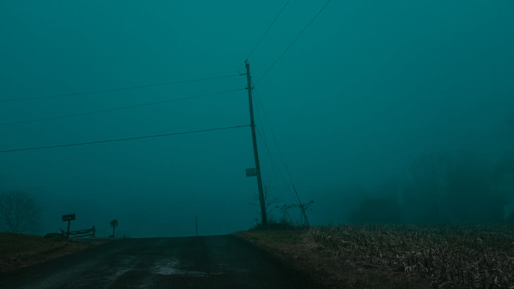 an empty road in the middle of a foggy field