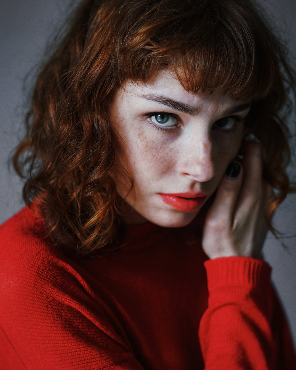 woman wearing red crew-neck sweater looking straight