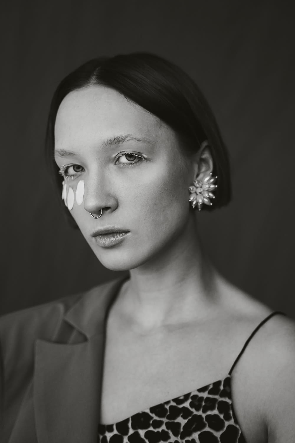 grayscale photography of woman wearing earrings and notched lapel blazer