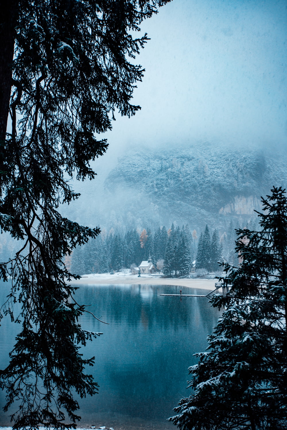 a lake surrounded by pine trees in the snow