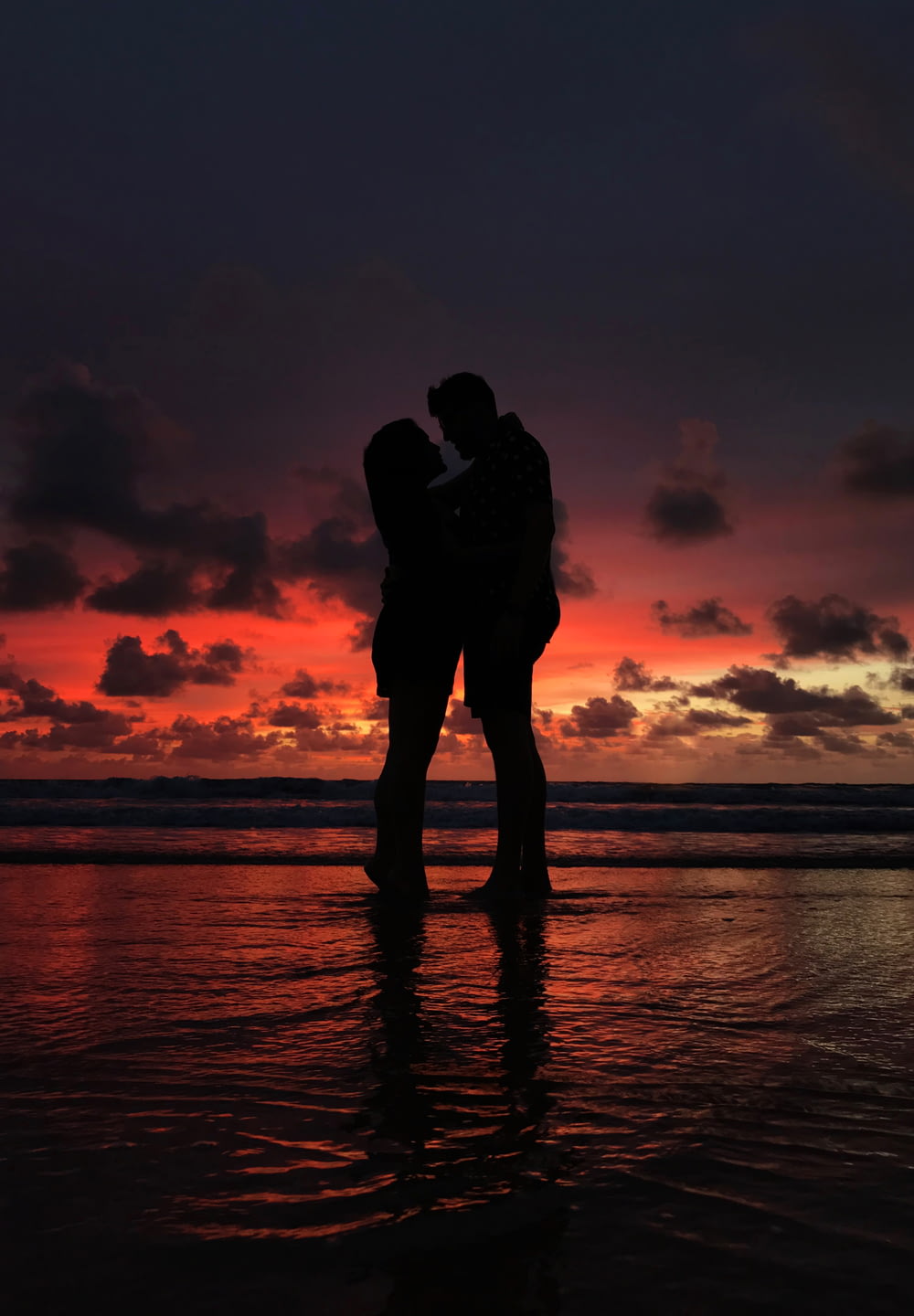 silhouette of man and woman hugging on shore