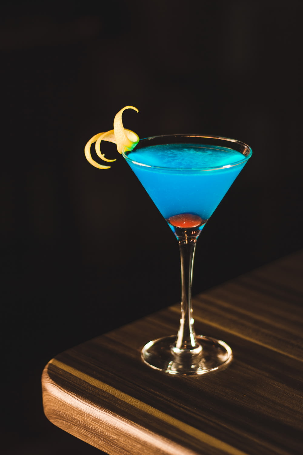 bevanda blu in bicchiere di vino sull'angolo del tavolo di legno
