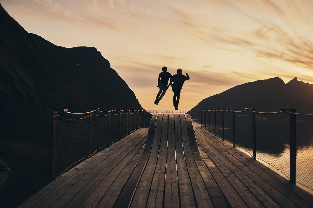 실루엣 view of couple jump on wooden hump beside of water