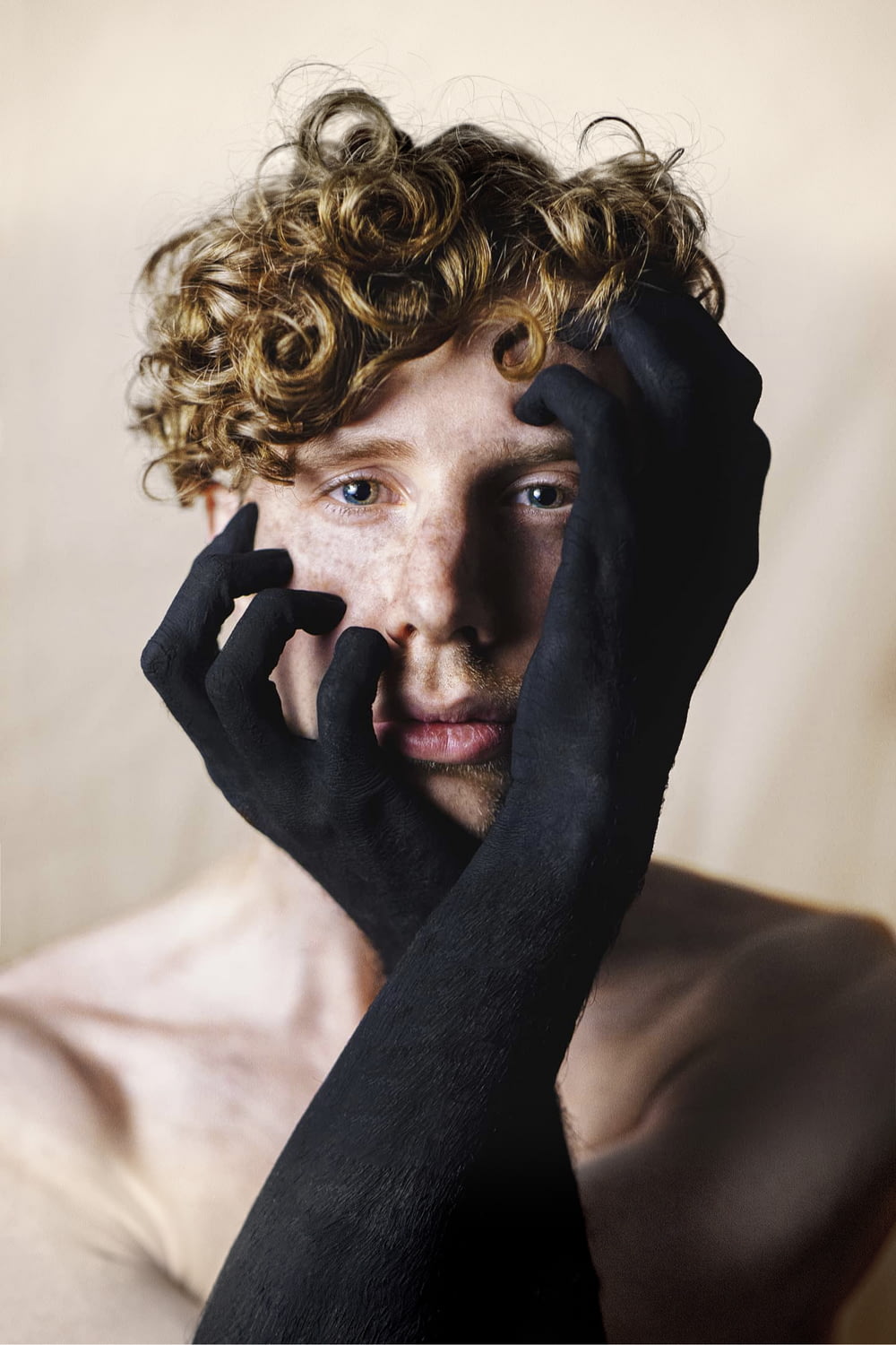 topless man touching his face with black paint