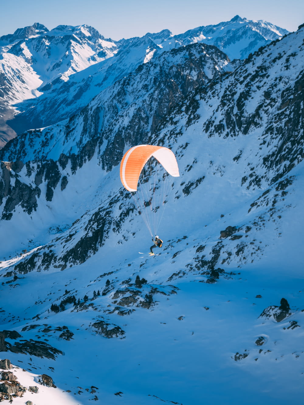 person riding parachute above glacier mountains and snowfield
