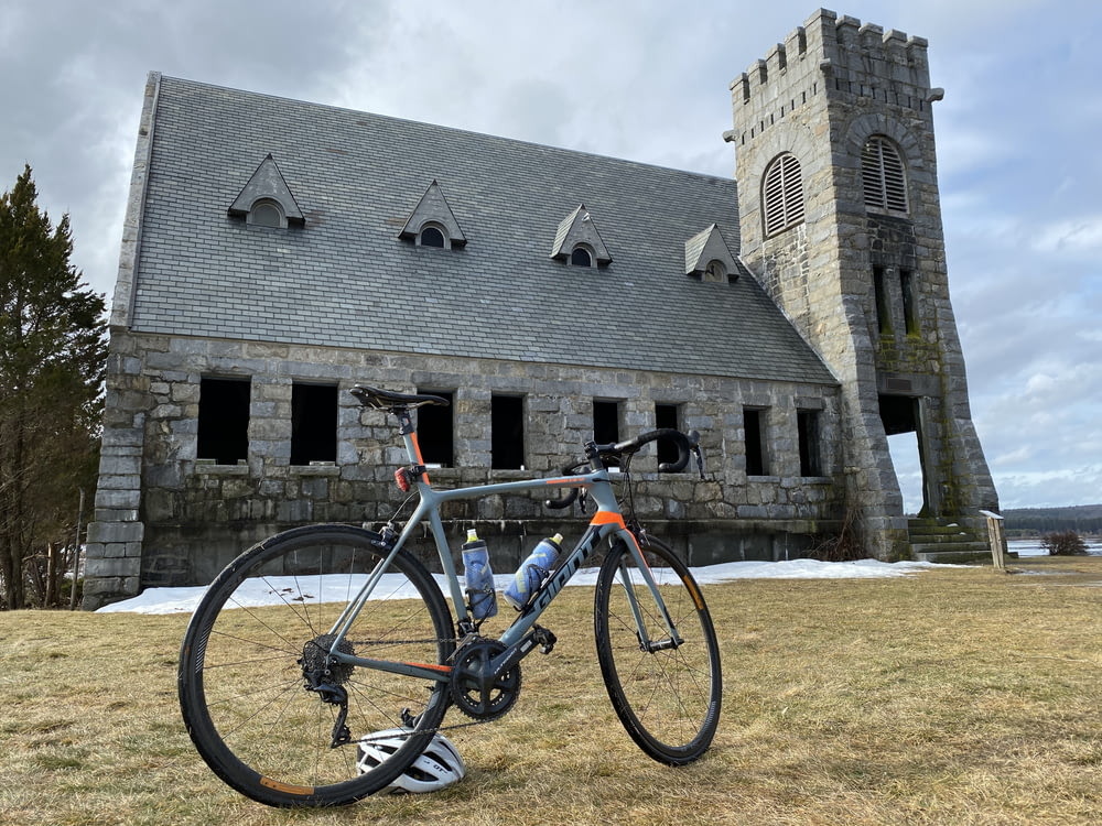 road bike parked on grass near building with tower during day