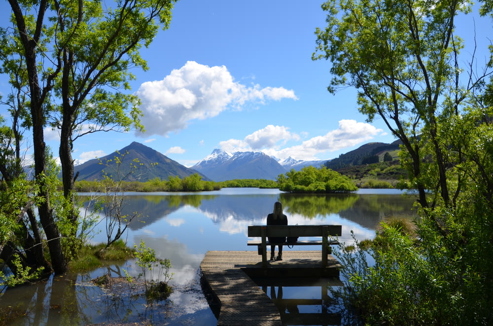 woman sitting on bench near lake