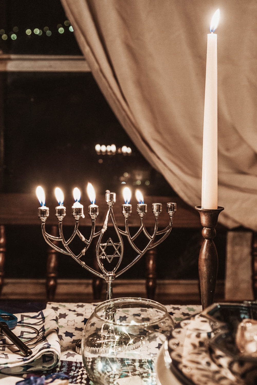 lighted taper candle on holder beside candelabrs