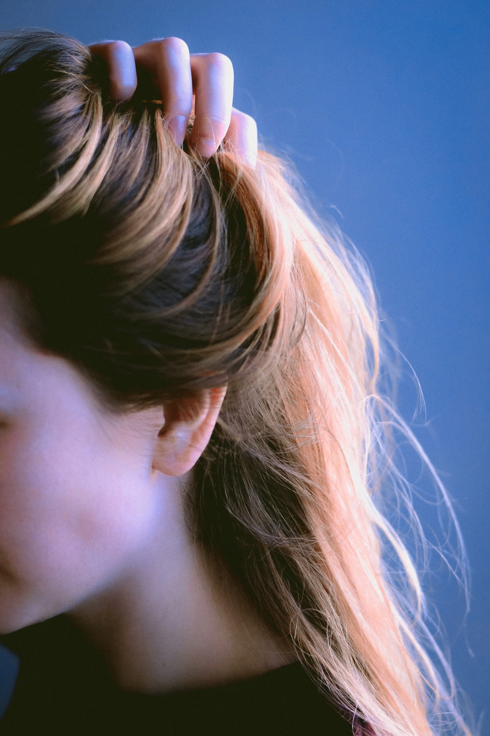 a close up of a woman's head with her hair in a pony tail