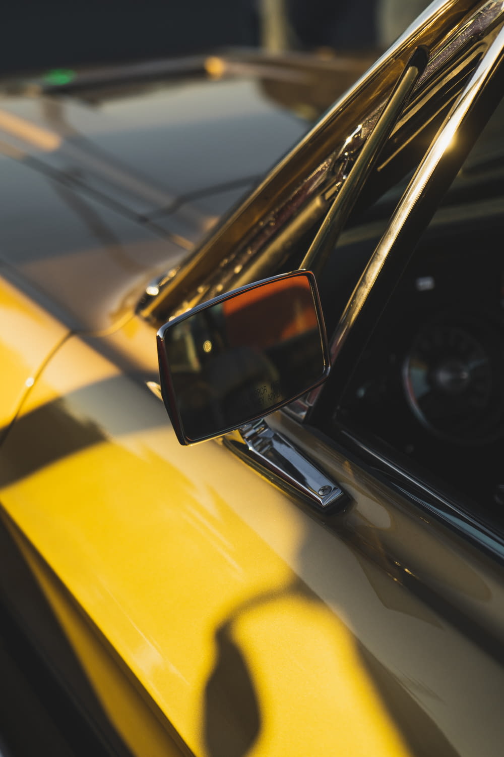 a close up of a yellow car with a mirror
