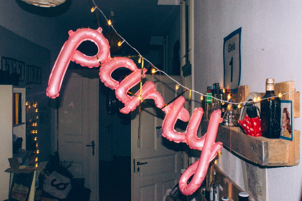 a pink balloon that says party hanging from a string