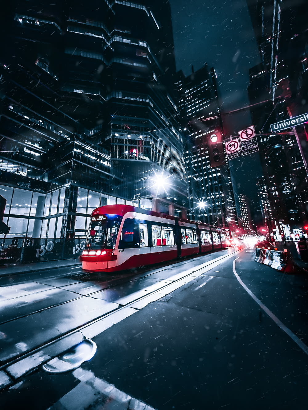 a red and white train traveling through a city at night
