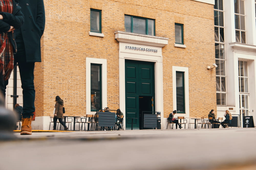 people sitting on bench in front of brown building during daytime