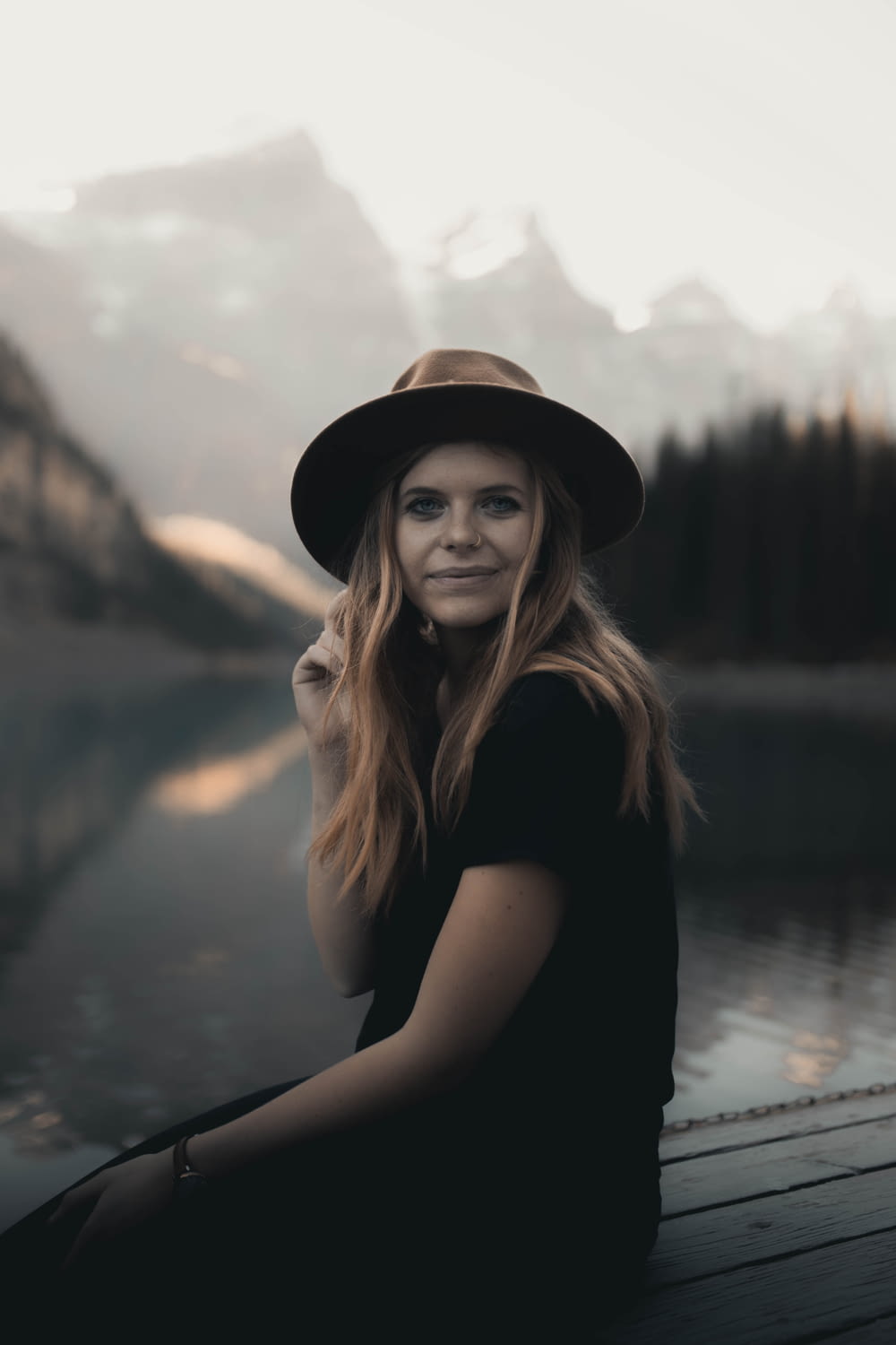 woman in black shirt and black hat standing near lake during daytime