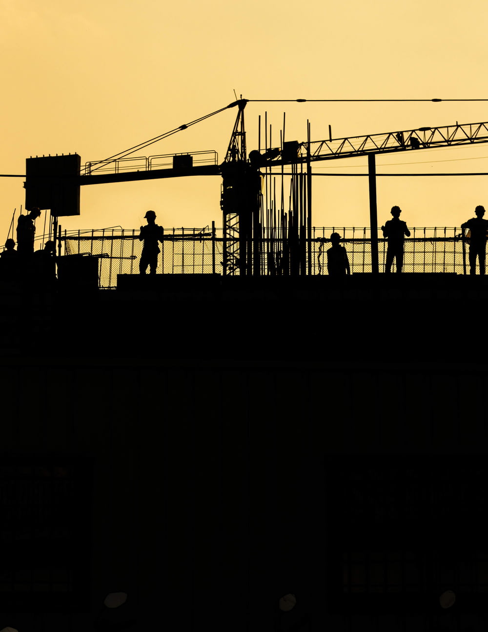 silhouette of people standing on tower crane during night time
