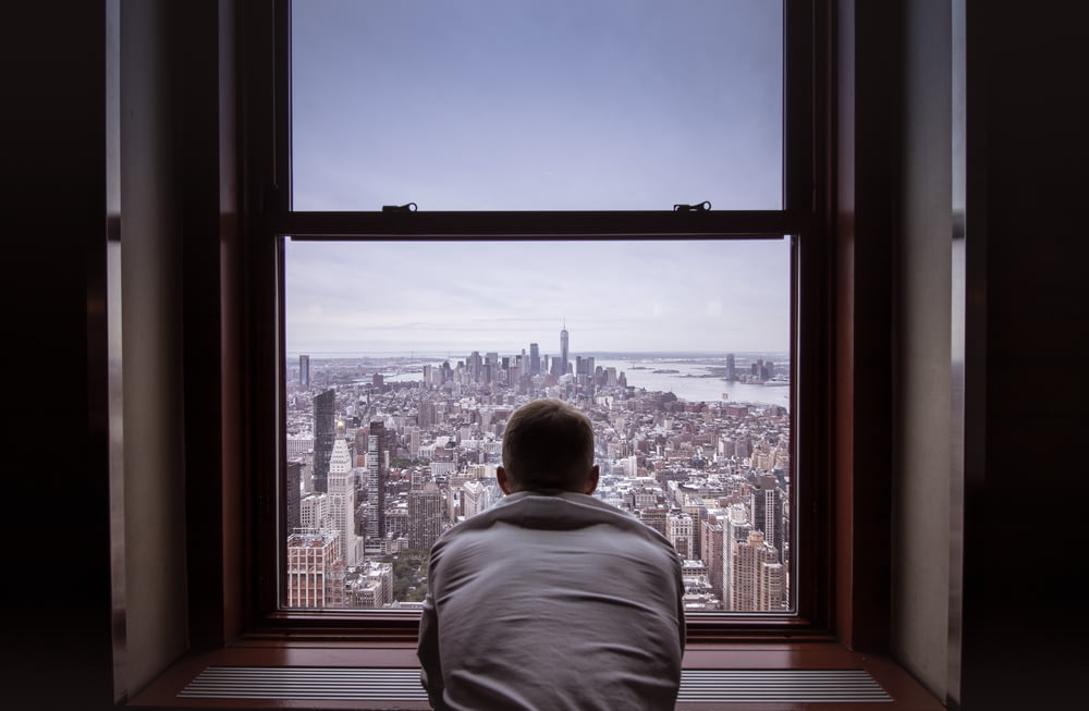 homme en chemise grise regardant les bâtiments de la ville pendant la journée