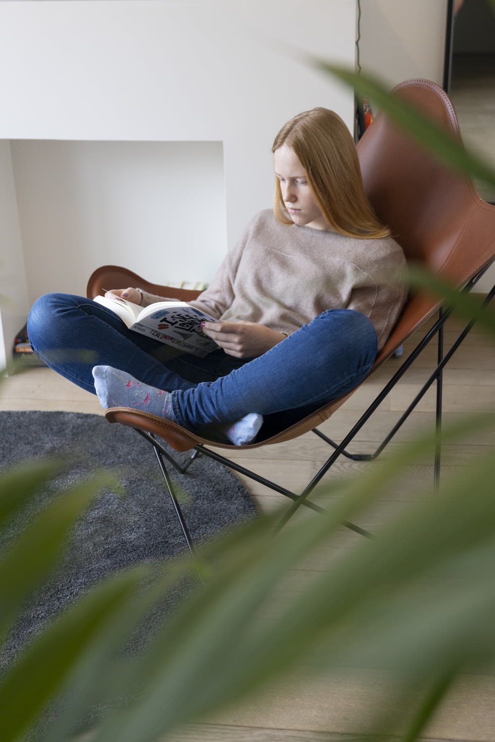 woman in gray sweater and blue denim jeans sitting on gray concrete floor