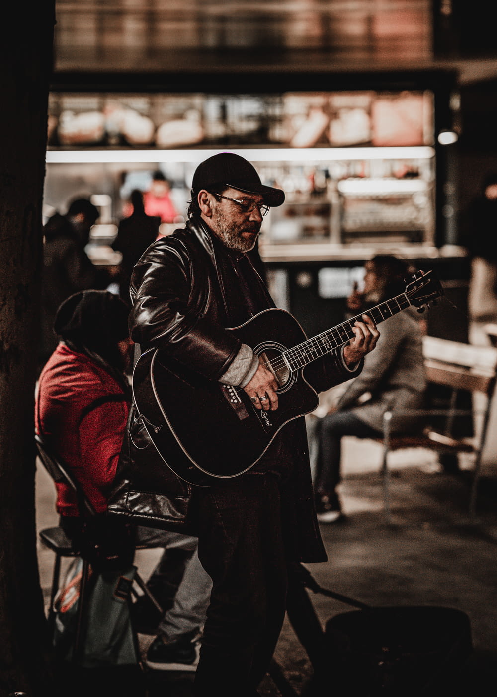 man in black jacket playing acoustic guitar