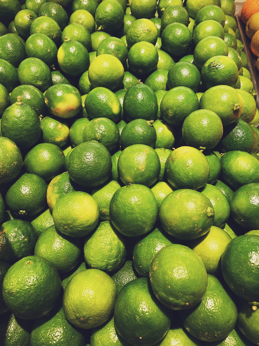 a pile of limes sitting on top of a pile of oranges