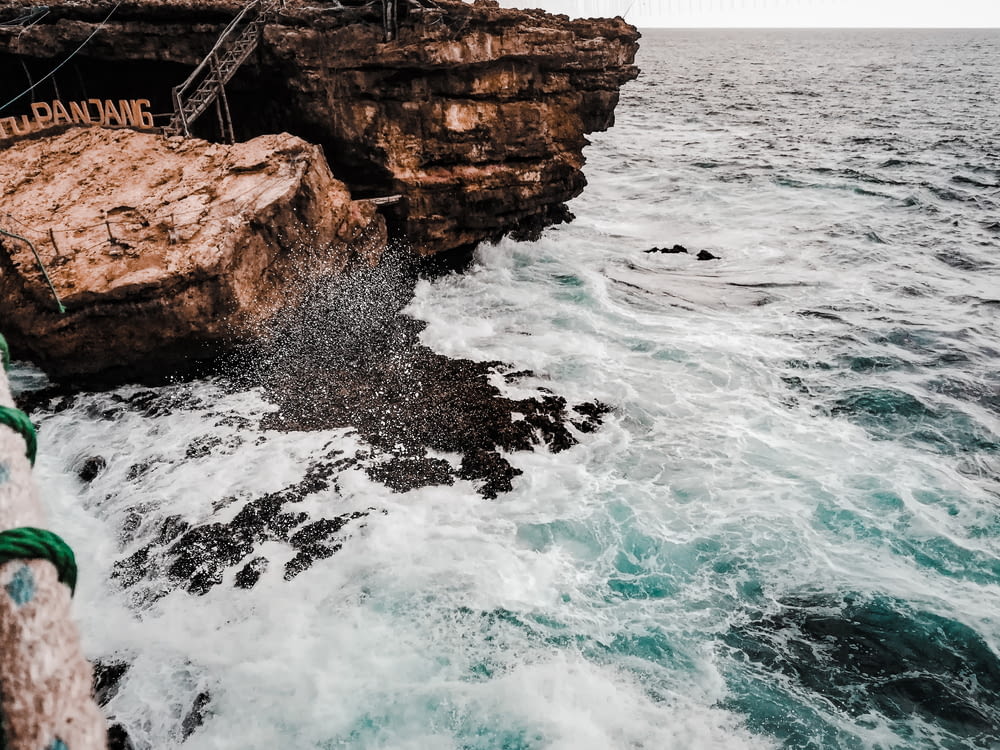 a rocky cliff next to the ocean with a rope