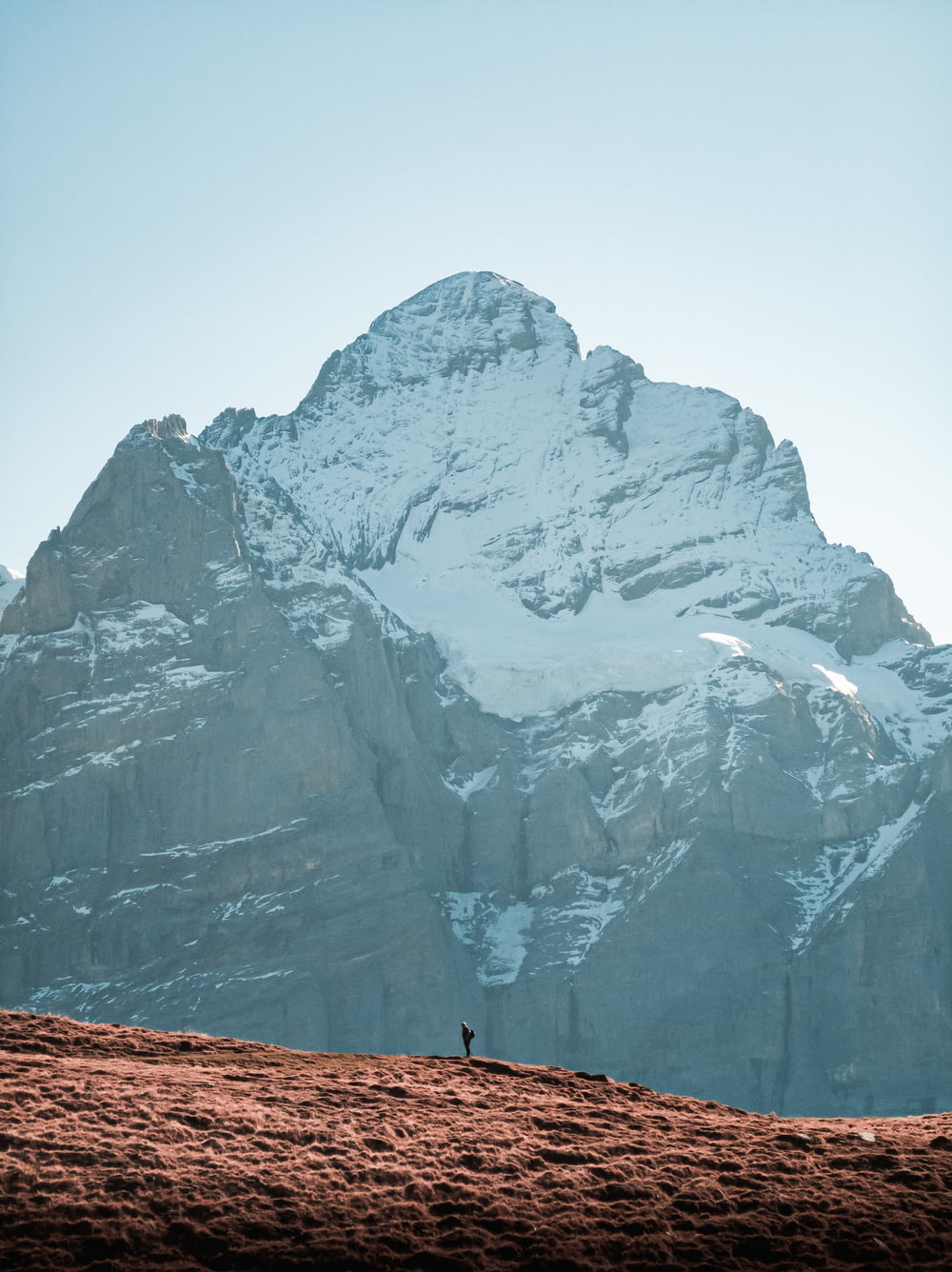 Una persona parada en la cima de una montaña cubierta de nieve