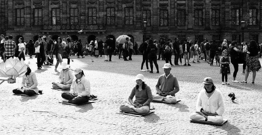 grayscale photo of people sitting on the street