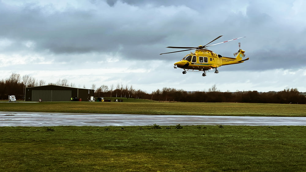 helicóptero amarelo e preto no campo de grama verde sob o céu nublado durante o dia