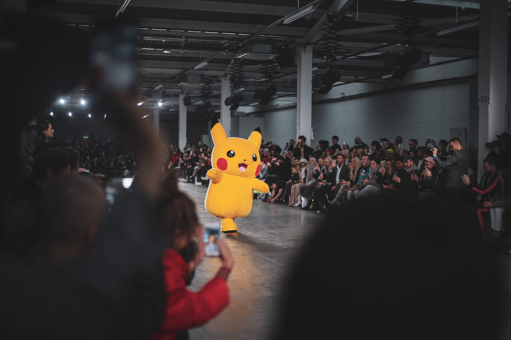 Personnes dans un concert avec la mascotte jaune Pokemon Pikachu