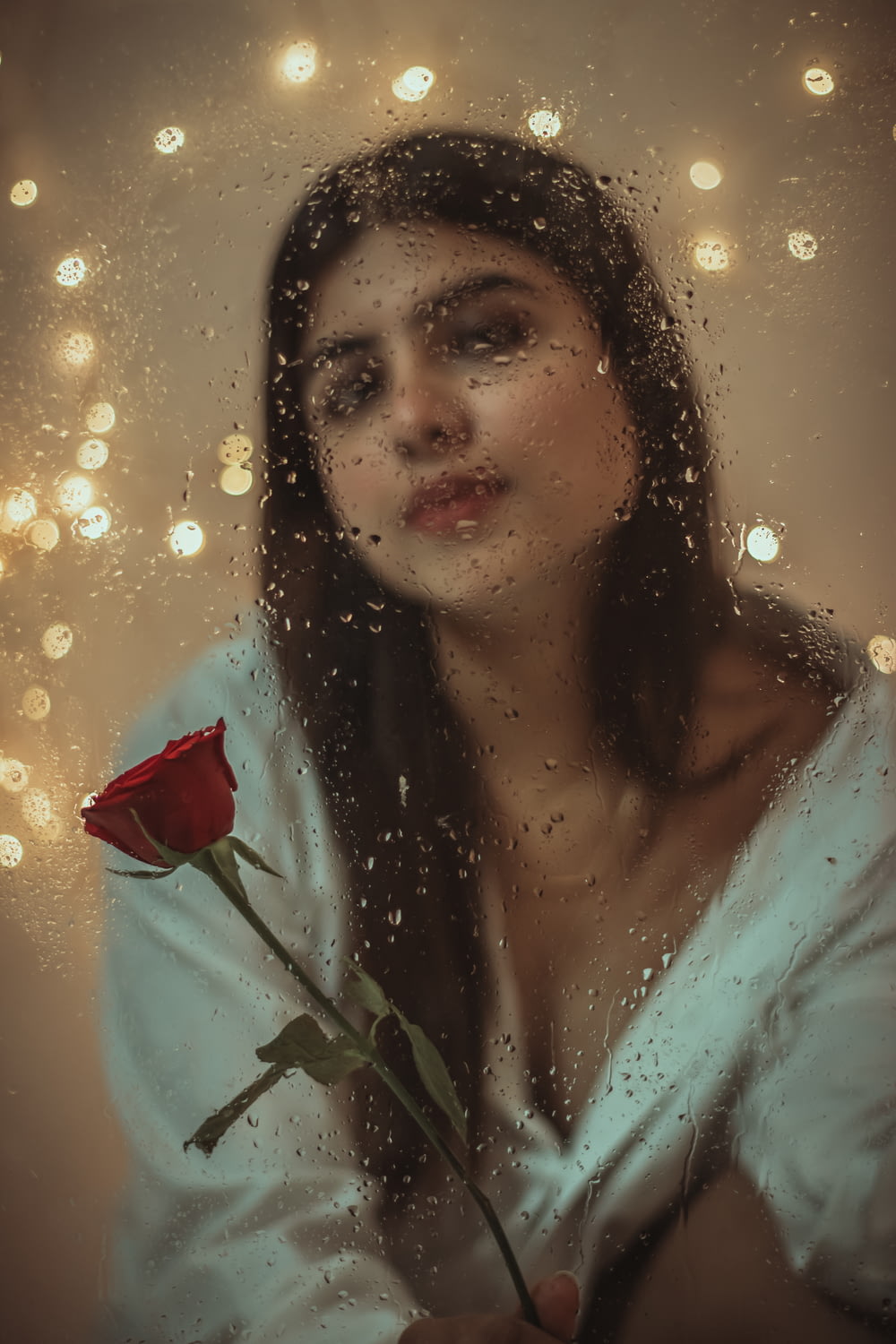 woman in white shirt holding red rose