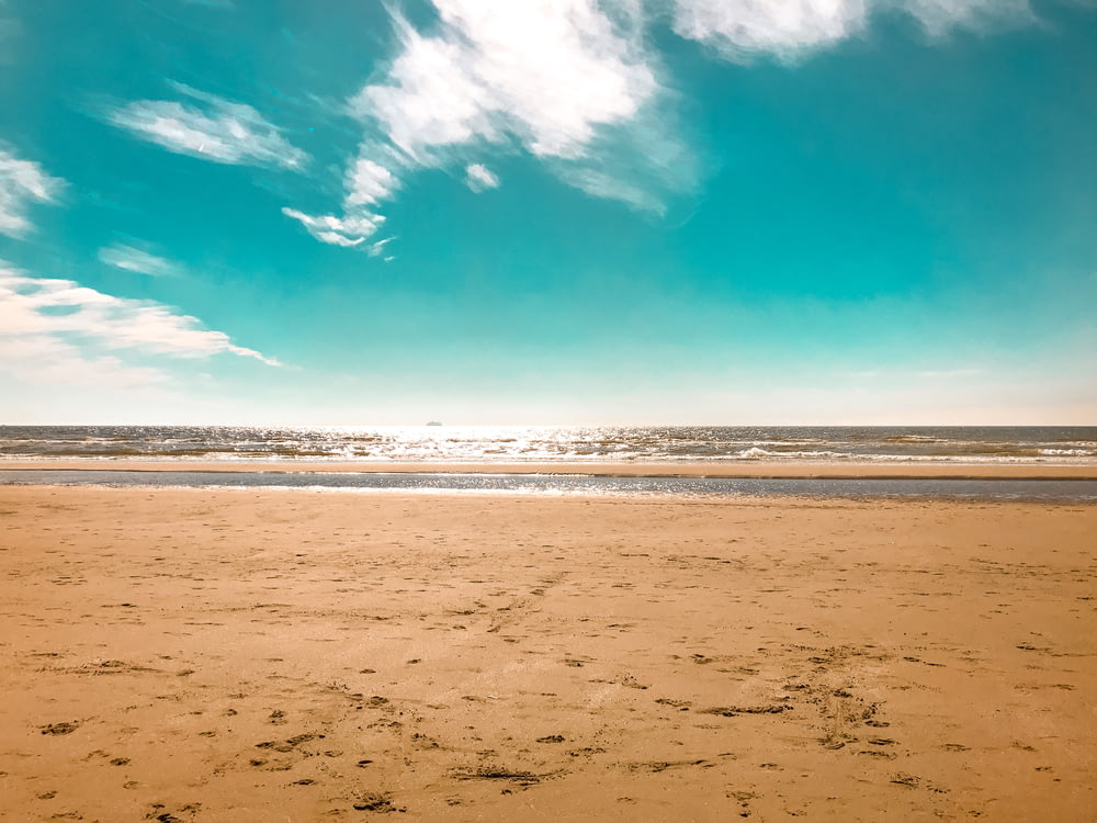 praia de areia branca sob o céu azul durante o dia